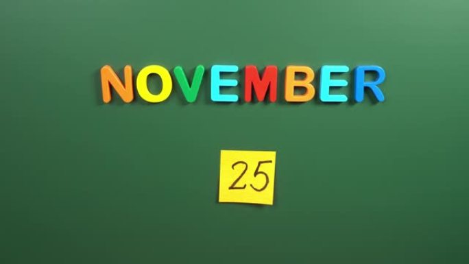 11月25日日历日用手在学校董事会上贴一张贴纸。25 11月日期。11月第二十五天。第25个日期编号
