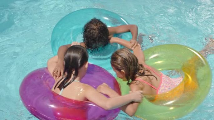 快乐的孩子在游泳池里游泳，带彩色游泳管充气玩具，孩子们嬉戏地在水上嬉戏玩耍，一起玩乐，享受暑假
