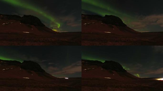 北极光在环城公路上，有汽车经过，留下了小路。在冰岛旅行时的极光狩猎之夜。停止在冰岛南部的狩猎极光