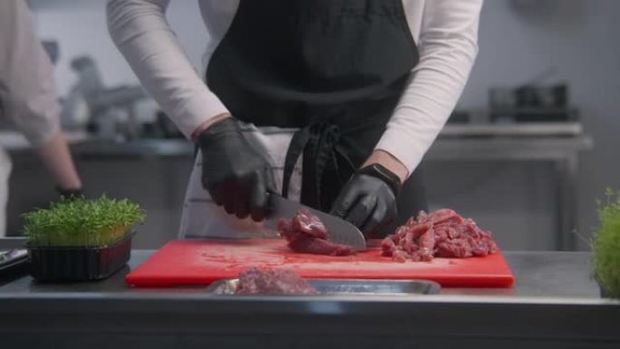 围裙厨师在切菜板上切肉