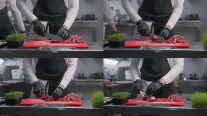 围裙厨师在切菜板上切肉