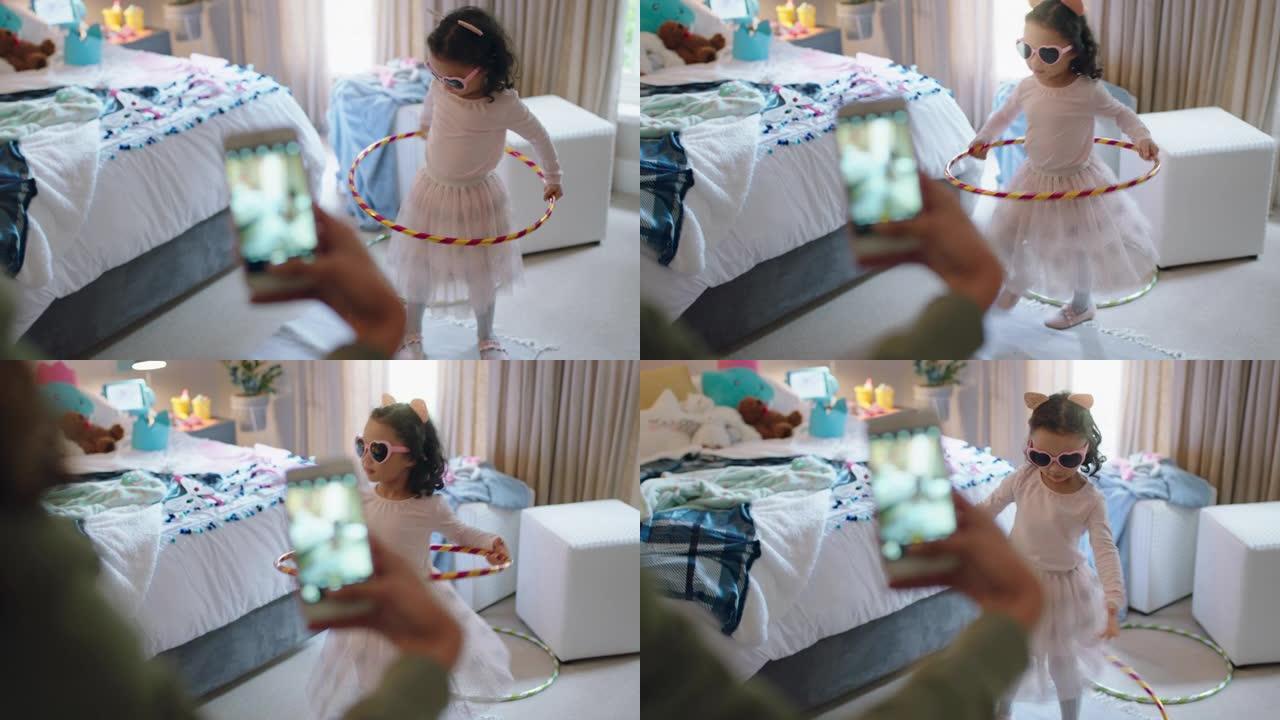 快乐的小女孩在卧室里玩呼啦圈跳舞妈妈用社交媒体上的智能手机分享拍照