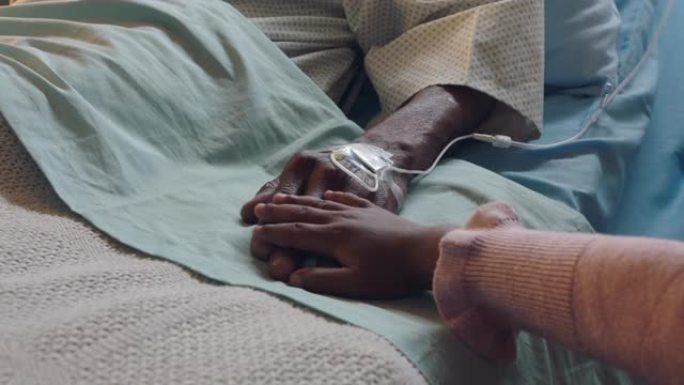 小女孩触摸祖父的手躺在医院的病床上，孩子在床边对祖父母从疾病中康复表示爱意。医疗保健家庭支持