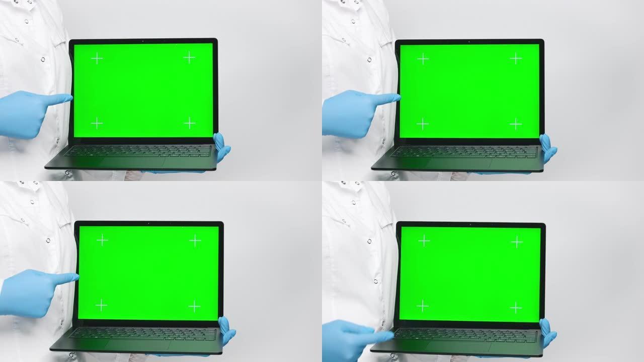 医生穿着白色外套和蓝色手套，拿着笔记本电脑，在显示带有跟踪点的绿色屏幕上，将手指指向屏幕。4k，复制