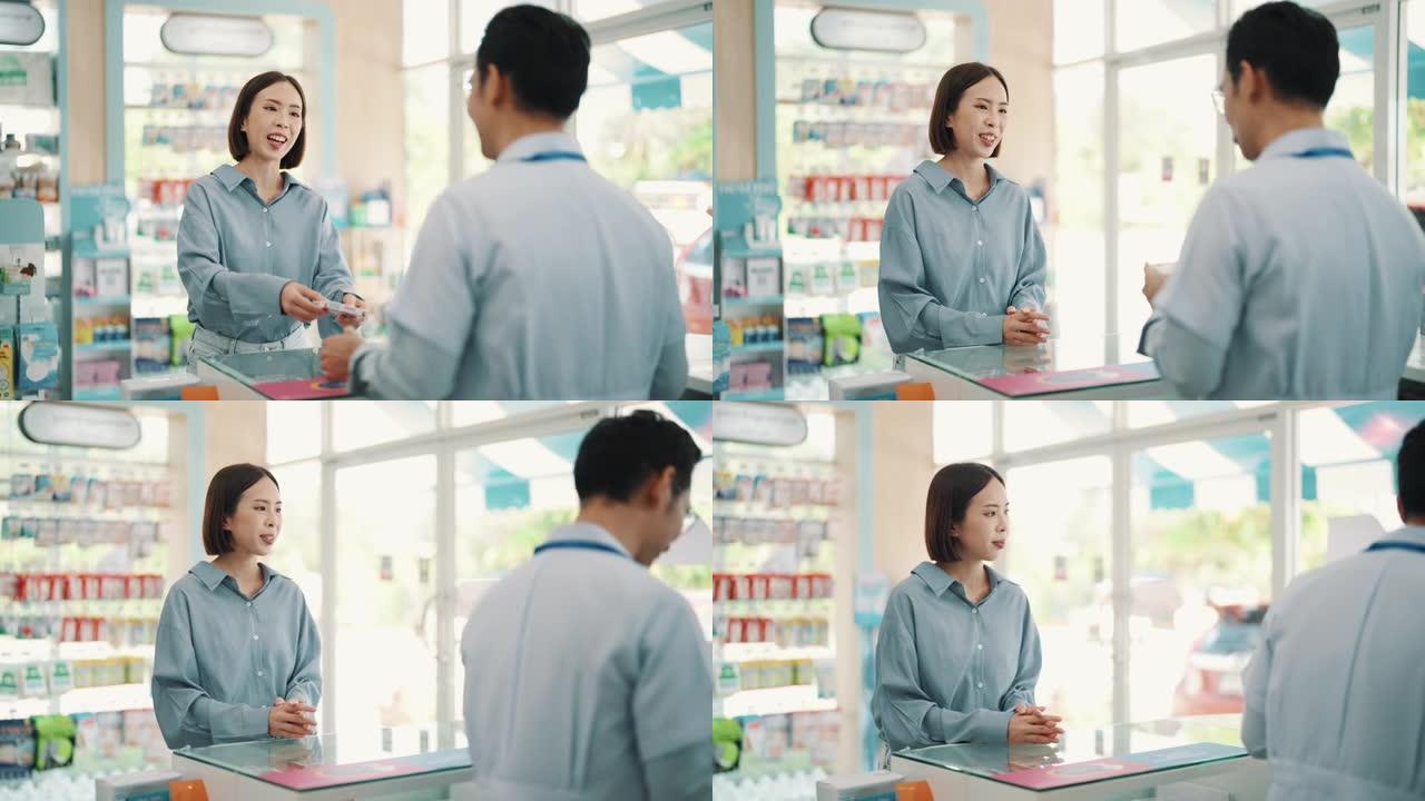 亚洲成熟男性药剂师在药房过道向年轻女性顾客解释。药剂师在药房向年轻女性顾客解释。