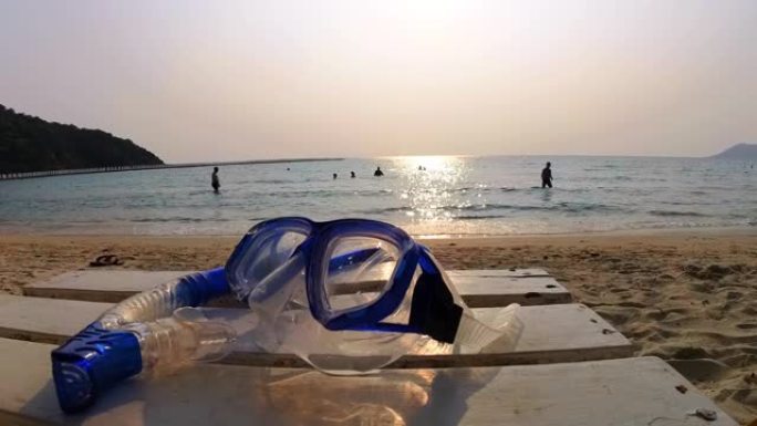 美丽的日落时，白色木桌上的浮潜面具。暑假的潜水设备、户外和海滩配件。人们喜欢在海边放松的海滩旅行。