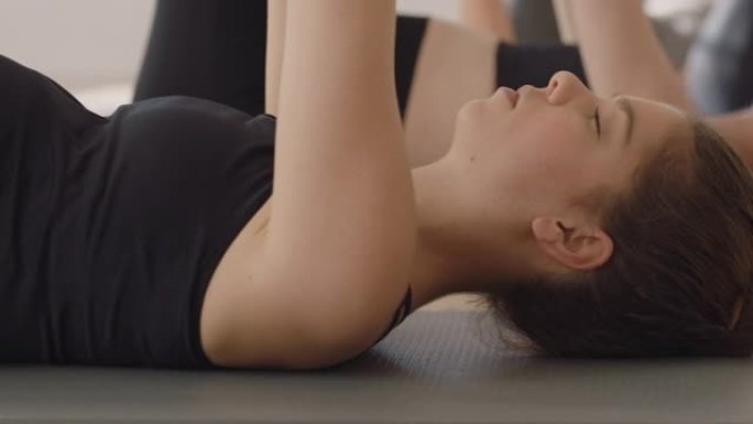 瑜伽课健康孕妇练习伸展躺在练习垫上享受工作室集体体能锻炼