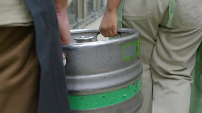 在啤酒厂，男人和女人的手在装满啤酒桶