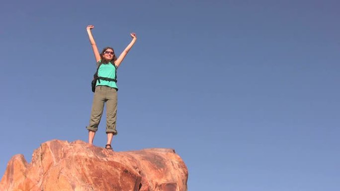 女徒步旅行者带着胜利的标志到达山顶