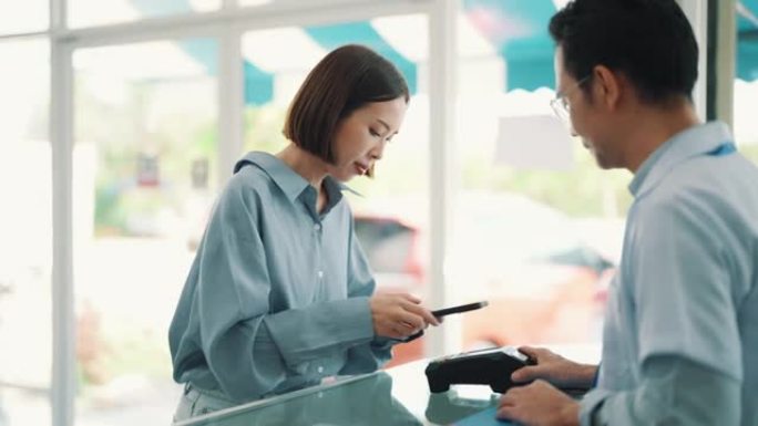 亚洲女性客户使用带有非接触式支付终端的NFC智能手机在药房购买处方药。