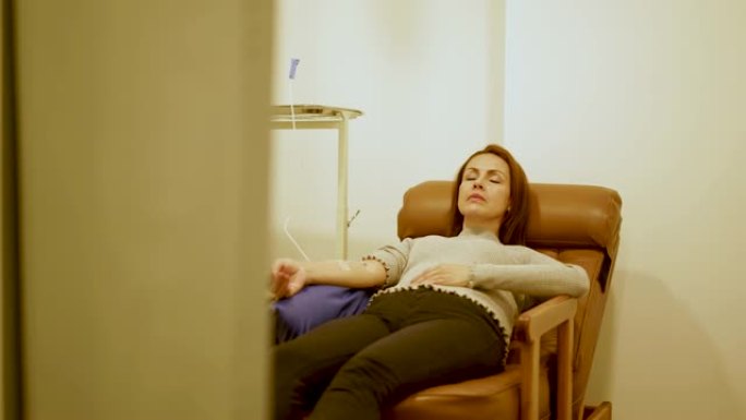 坐在扶手椅上的女人直接将一定剂量的维生素注入静脉