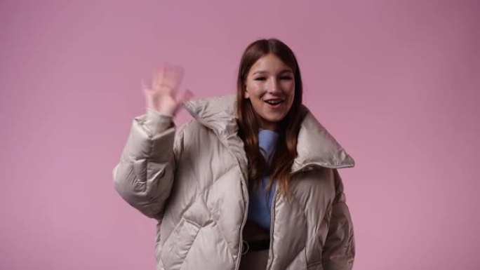 可爱的女孩在粉色背景上挥手打招呼的4k视频。
