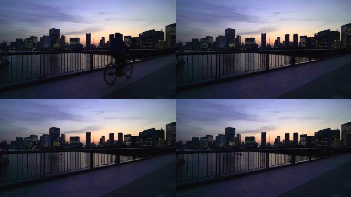 东京铁塔和黄昏时的城市景观。穿越筑地大桥的自行车。