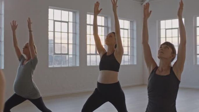瑜伽课教练在日出时在健身室教健康孕妇练习战士姿势享受团体训练锻炼