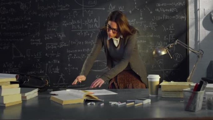 大学教室里年轻女教师的肖像，使用笔记和带有数学公式的黑板工作。在大学图书馆学习的理科生看着相机微笑