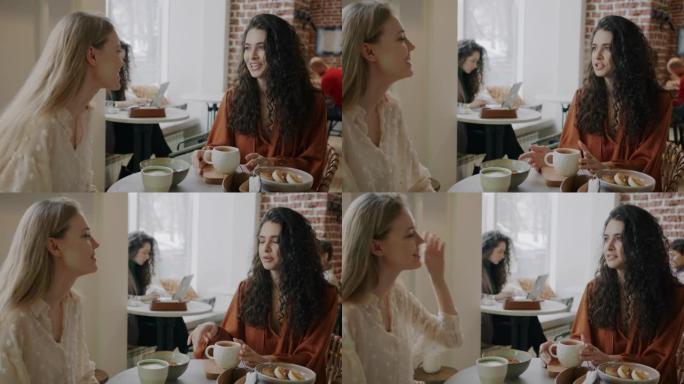 美丽的年轻女性朋友坐在咖啡馆的餐桌旁谈笑风生，一起享受休闲时光