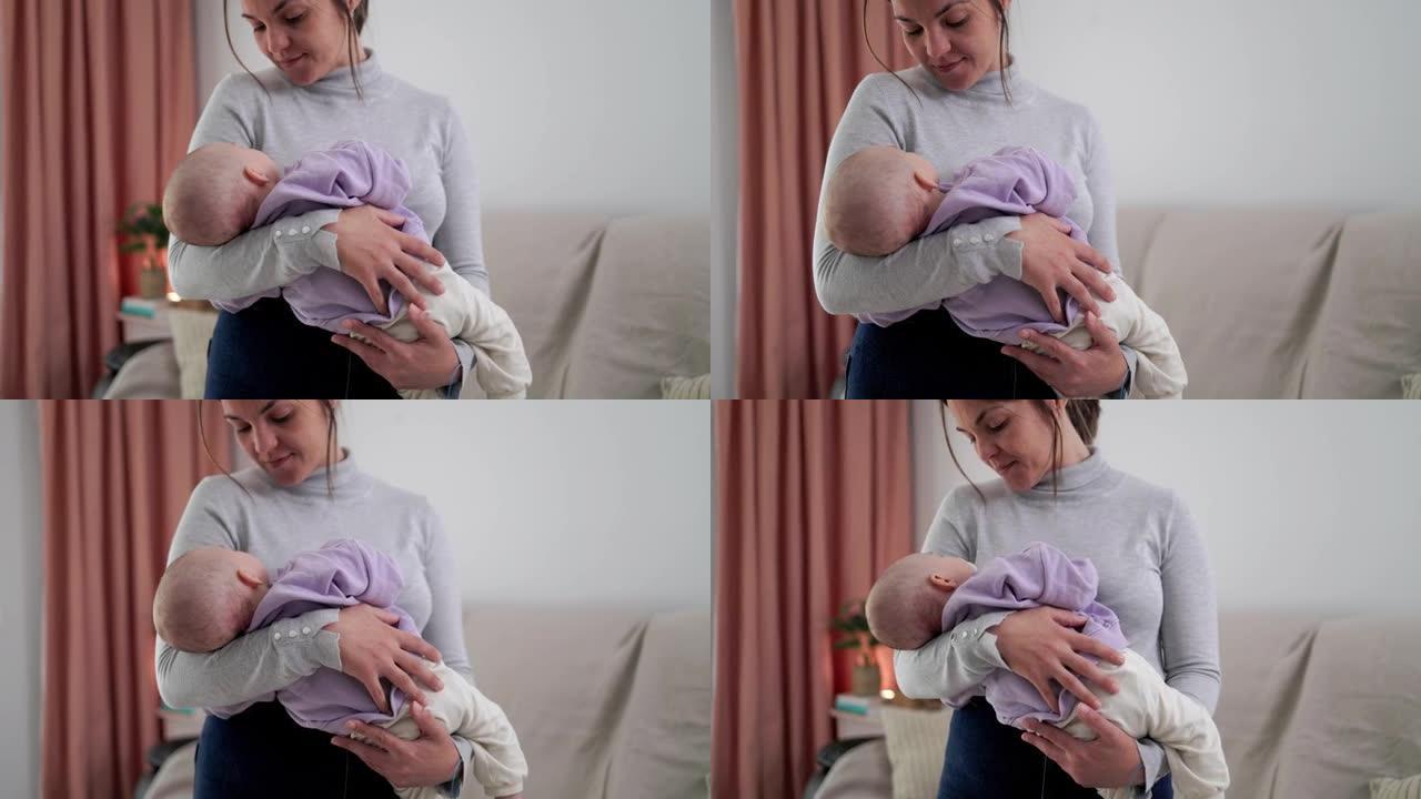 年轻的母亲在家里的沙发上拥抱她的新生婴儿