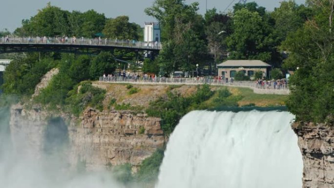 尼亚加拉瀑布 (Niagara Falls) 的强大水流，背景是游客步行的公园