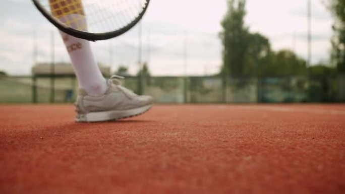 女子网球运动员用球拍从球场上捡起球进行发球。