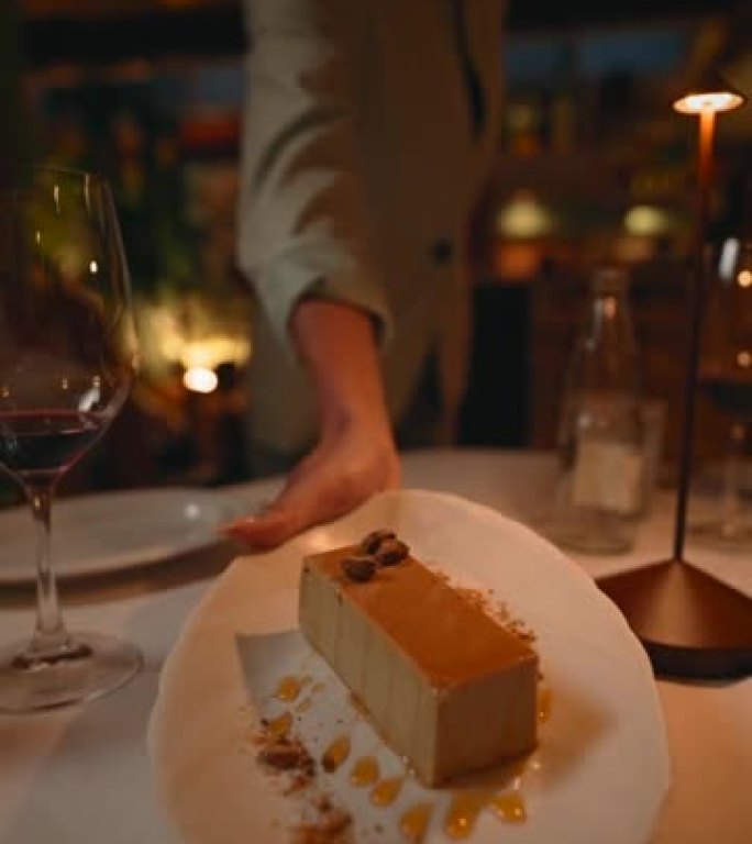 服务员端上餐桌的焦糖奶油蛋糕的垂直慢动作视频