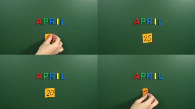4月20日日历日用手在学校董事会上贴一张贴纸。20 4月日期。4月的第二十天。第20个日期号。20天
