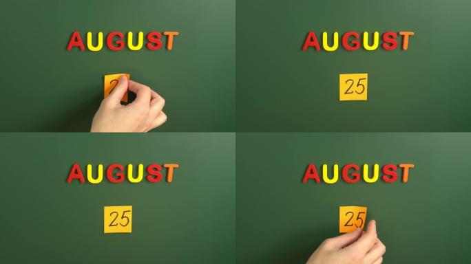8月25日日历日用手在学校董事会上贴一张贴纸。25 8月日期。8月第二十五天。第25个日期编号。25
