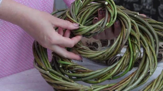 一个女人把用藤蔓编织的自制花环放在一起。各种大小的花环。特写。