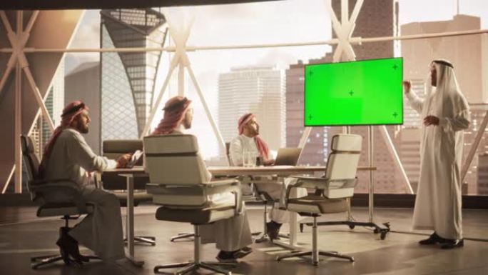 阿拉伯商人向一群沙特投资者展示数据。带有绿屏模拟显示的电视屏幕。现代办公室会议室商务会议演示