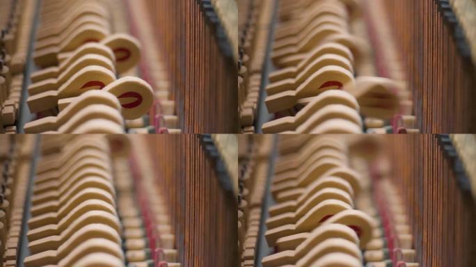 几把钢琴锤在一架由轻质木材制成的老式家用钢琴立式钢琴中敲击琴弦。