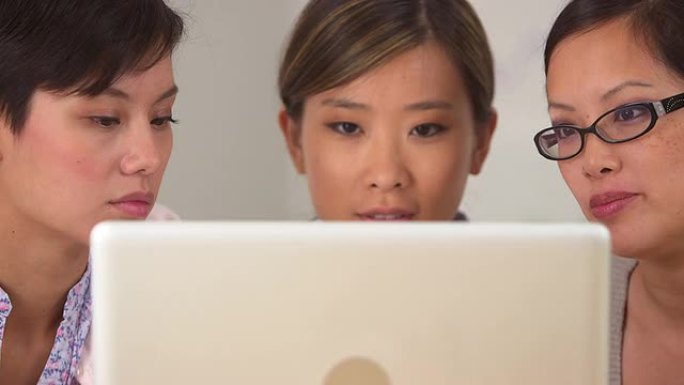 三个亚洲女商人盯着笔记本电脑