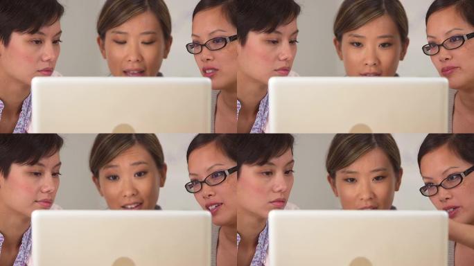 三个亚洲女商人盯着笔记本电脑