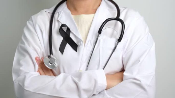 黑色素瘤和皮肤癌，疫苗伤害宣传月和安息的概念。手持黑丝带的医生
