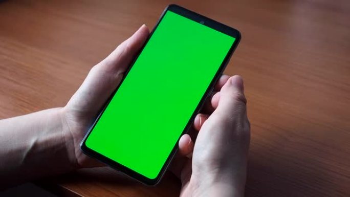 智能手机或色度键的绿色屏幕。女人的手握着手机，点击触摸屏。特写模拟