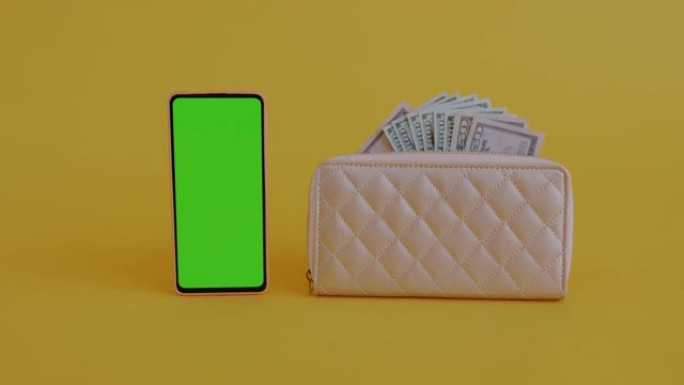 缩小女性钱包和绿色屏幕色度键智能手机中的金钱，以黄色背景显示