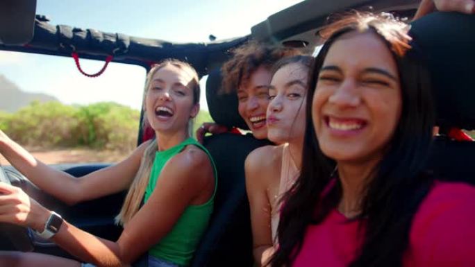 在公路旅行中，笑的女性朋友在敞开车中拉脸的肖像