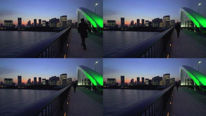 东京铁塔和黄昏的城市景观。筑地桥上行走的人们