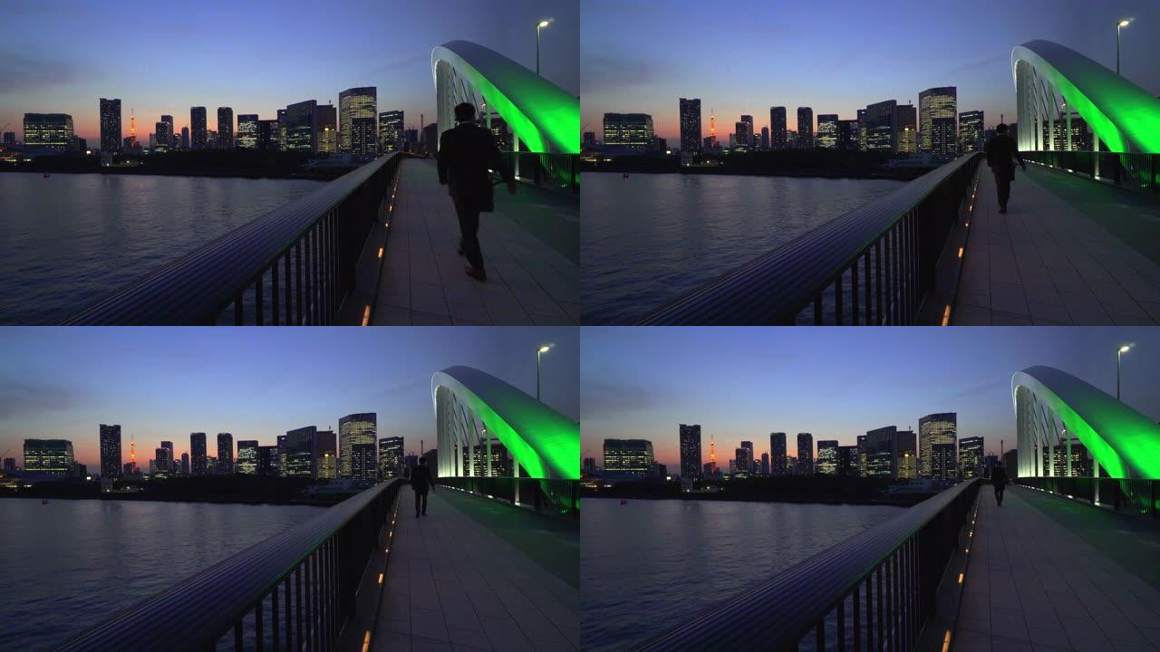 东京铁塔和黄昏的城市景观。筑地桥上行走的人们