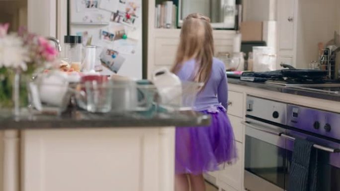 快乐芭蕾舞女演员穿着紫色芭蕾舞短裙在厨房跳舞，玩得开心，表演有趣的舞蹈动作，在家享受周末庆祝
