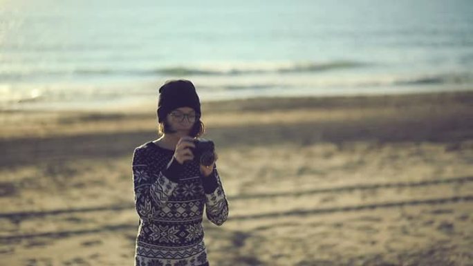 十几岁的女孩用一台旧的电影相机在海滩上拍照