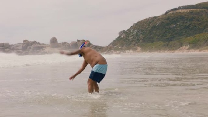 有趣的非洲裔美国男子穿着鳍状肢在海水中走在海滩上准备游泳，享受海洋4k的夏天