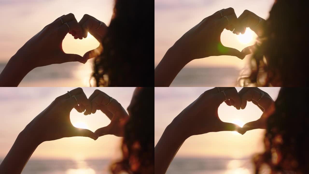 clsoe up女人双手做心形手势，手持美丽的日落耀斑，在海滩上享受浪漫的假期