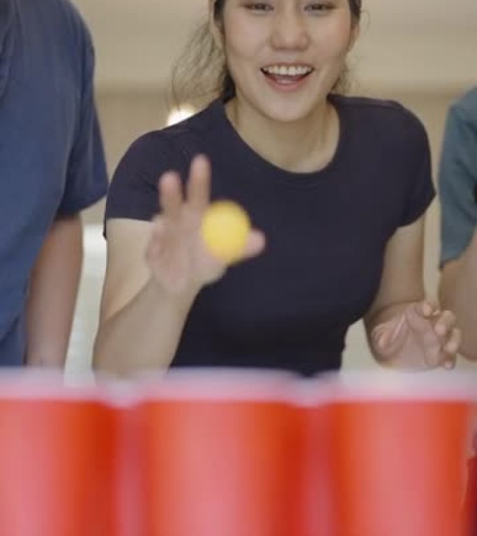 一次性杯子上的低角度平移镜头显示，一群年轻开朗的朋友在一次聚会上玩啤酒乒乓球，唯一的女人快乐地赢得了