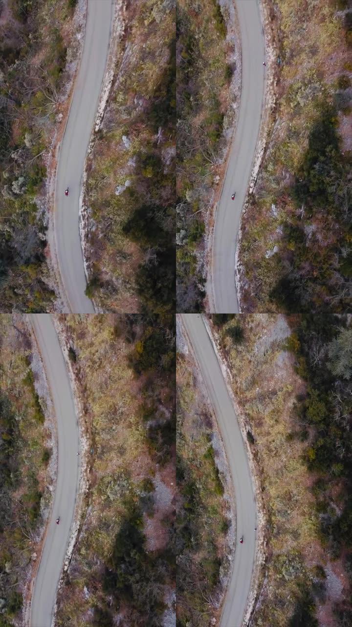 骑自行车的人攀登山路的空中无人机视图