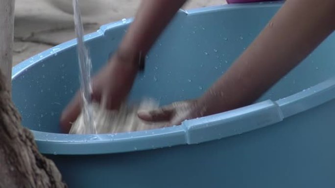 一名年轻女子的手在阿根廷卡塔马卡染色前洗羊毛。特写。