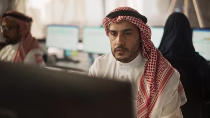 在金融科技初创公司从事台式计算机工作的中东工程师的肖像。阿拉伯软件开发人员正在研究新的想法来解决技术