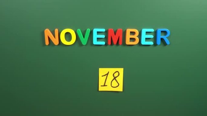 11月18日日历日用手在学校董事会上贴一张贴纸。18 11月日期。11月的第十八天。第18个日期编号