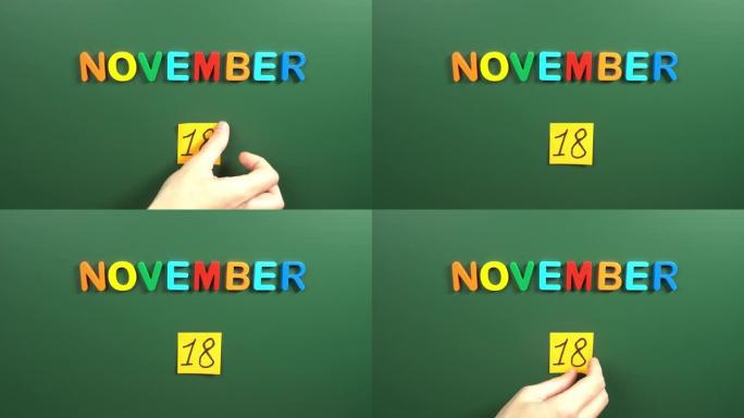 11月18日日历日用手在学校董事会上贴一张贴纸。18 11月日期。11月的第十八天。第18个日期编号