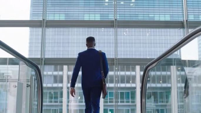 年轻的非裔美国商人在自动扶梯上，成功的男性高管到达公司办公楼，看着窗外，提前计划4k