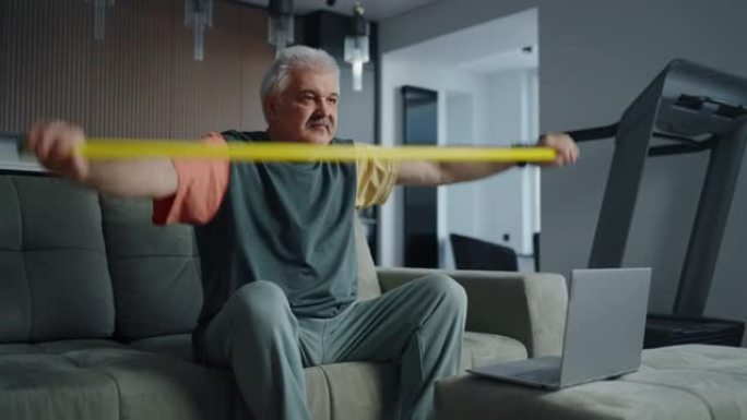 老年人的家庭健身，成熟的男人用棍子进行体育锻炼以促进脊柱健康