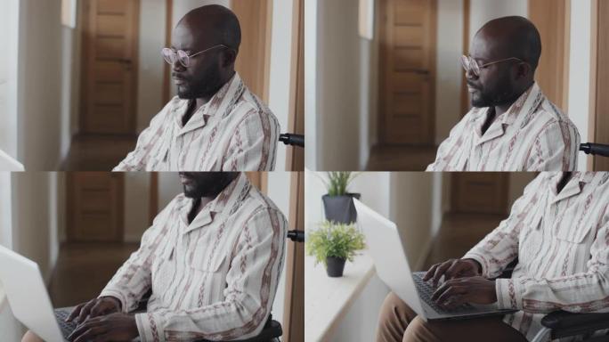 坐在轮椅上的非裔美国人在笔记本电脑上打字